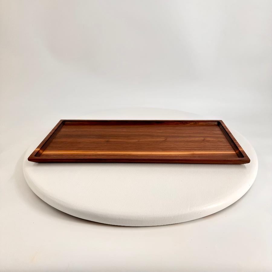 view of large walnut tray with outer raised edge and angular frame.